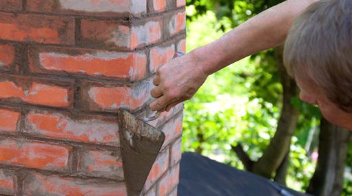 Trowel tucking fresh mortar along a stack flank