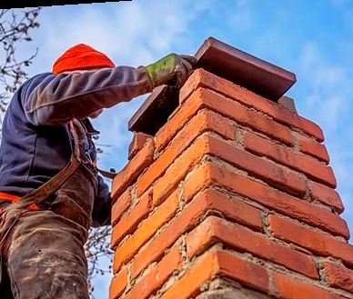 Mason hoisting a capstone into place at the top of a tall stack